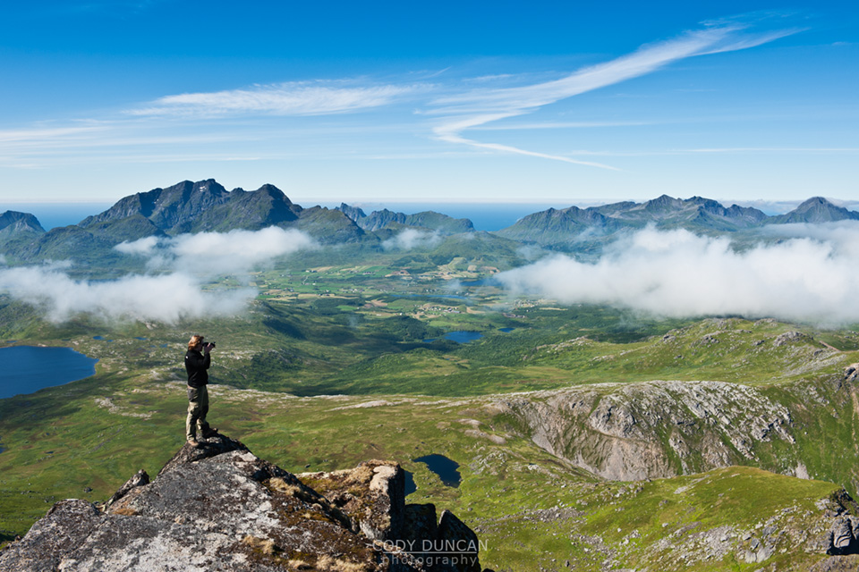 Photographer takes photos of scenic mountain landscape from summit of Justadtind, Vestvagoy, Lofoten islands, Norway