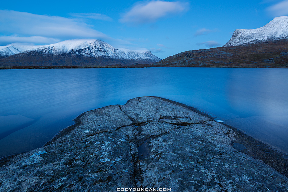 Snow covered mountain rise above lake Radujavri along Kungsleden trail, Lappland, Sweden