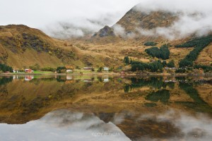 Reflection of misty mountains and village, Rolvsfjord, Lofoten Islands, Norway