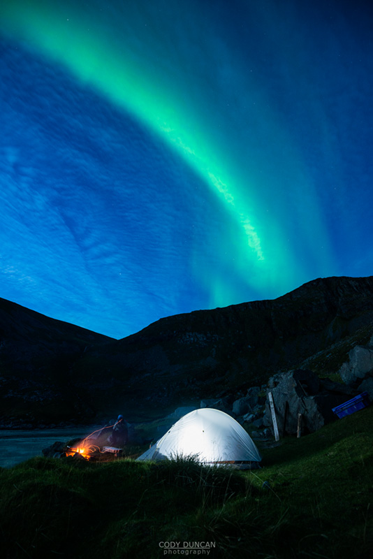 Illuminated tent with Northern Lights in sky at Kvalvika beach, Moskenesoy, Lofoten Islands, Norway