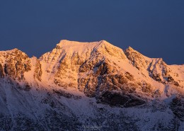 Winter sunset illuminates snow covered mountain peaks, Flakstadøy, Lofoten Islands, Norway