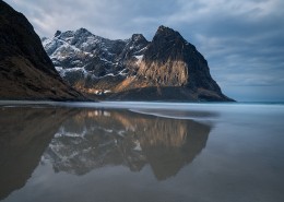 Mountain peaks rise over empty sands at Kvalvika beach, Moskenesøy, Lofoten Islands, Norway