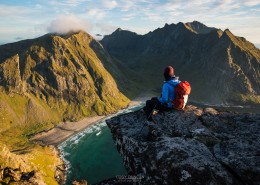 hiker enjoying view of Kvalvika beach from near summit of Ryten, Moskenesoy, Lofoten Islands, Norway