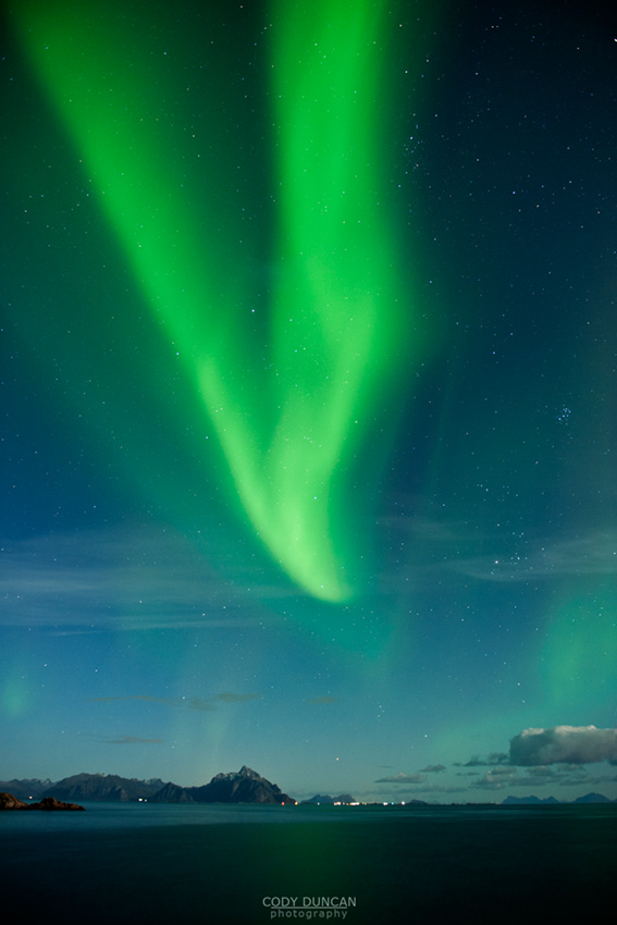 Northern Lights fill sky over sea and mountains, Stamsund, Vestvagoy, Lofoten islands, Norway