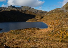 Hiker walking through autumn mountain landscape near lake Vikjordvatnet, Vestvågøy, Lofoten Islands, Norway