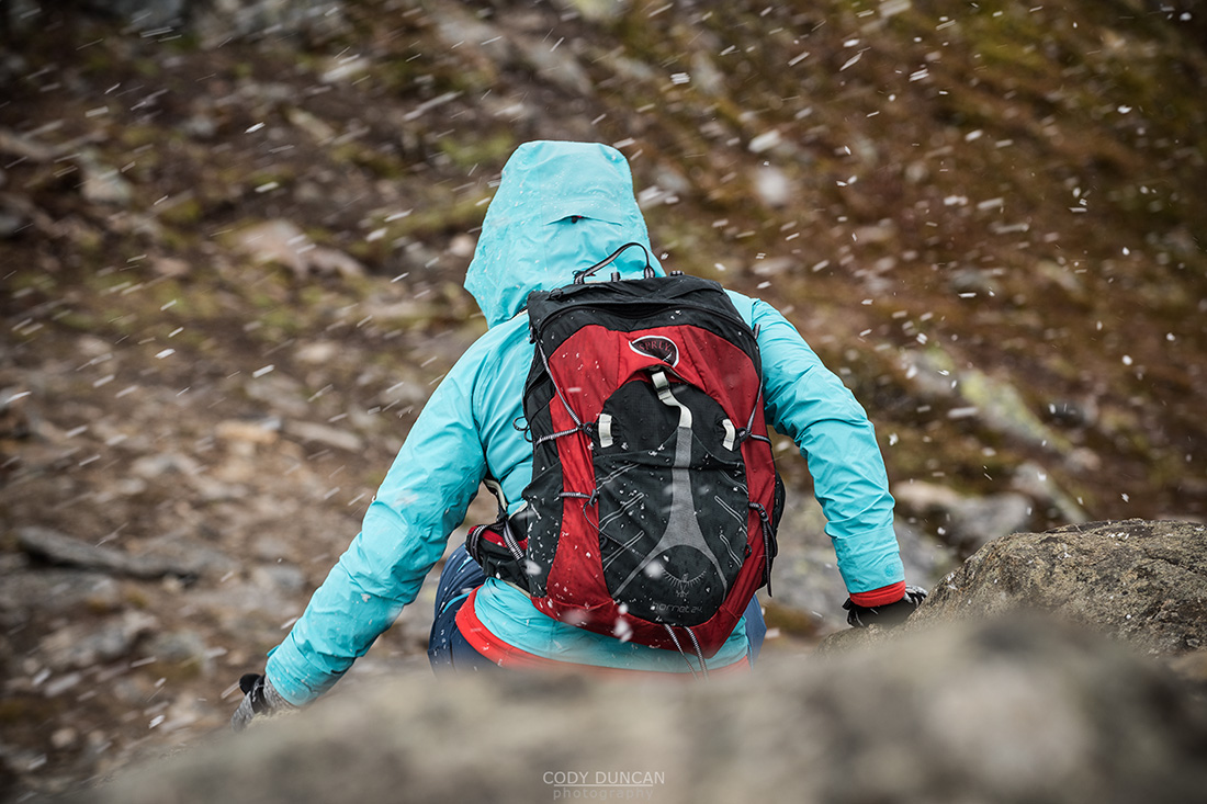 Female hiker is summer snow flurry near summit of Festvågtind, Austvågøy, Lofoten Islands, Norway