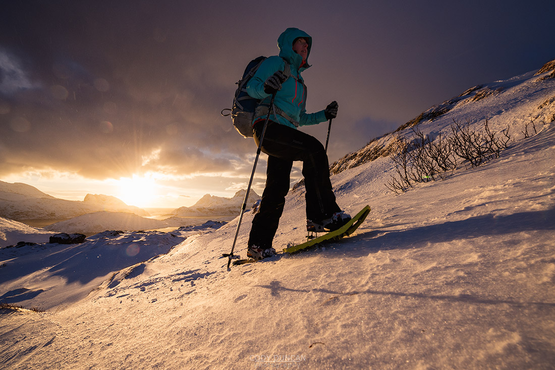 Female hiker with snowshoes at winter dawn on way to Ryten, Moskenesøy, Lofoten Islands, Norway