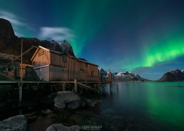 Northern Lights - Aurora Borealis shine in sky over abandoned Rorbu cabin, Valen, near Reine, Moskenesøy, Lofoten Islands, Norway