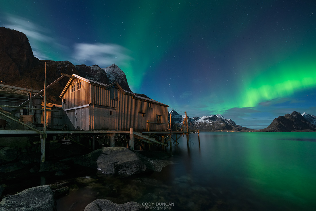 Northern Lights - Aurora Borealis shine in sky over abandoned Rorbu cabin, Valen, near Reine, Moskenesøy, Lofoten Islands, Norway