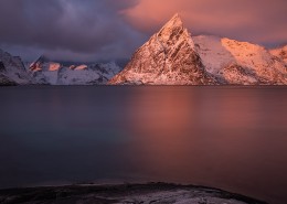 Olstind mountain peak glows pink at sunrise, Toppøy, Moskenesøy, Lofoten Islands, Norway