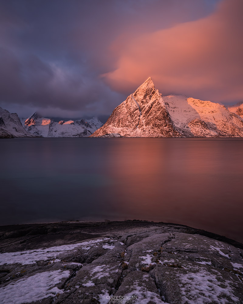 Olstind mountain peak glows pink at sunrise, Toppøy, Moskenesøy, Lofoten Islands, Norway