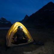 tent illuminated at night while wild camping at scenic Horseid beach, Moskenesøy, Lofoten Islands, Norway