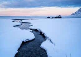 Small river running through snow on Skagsanden beach, Flakstadøy, Lofoten Islands, Norway