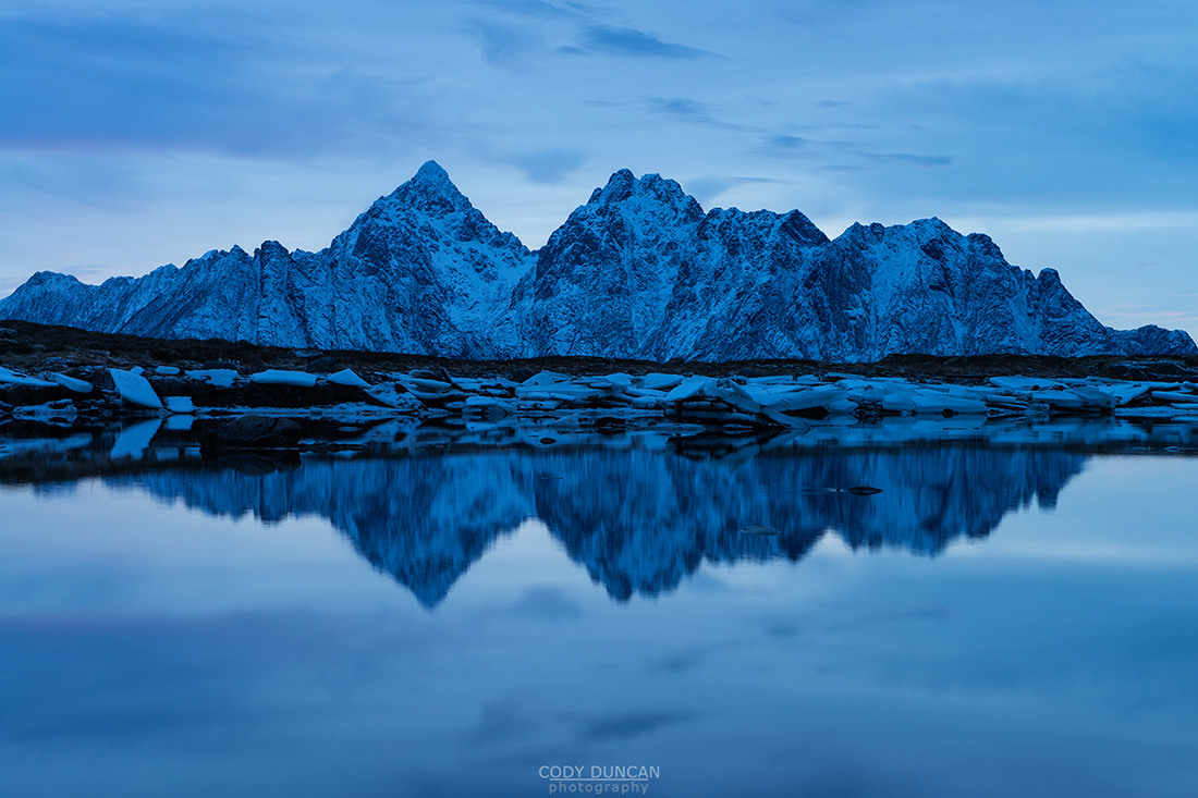 Reflection of Vågakallen mountain peak over coastline, Vestvågøy, Lofoten Islands, Norway